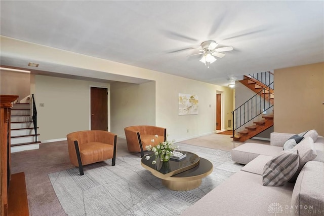 carpeted living area with baseboards, stairway, and ceiling fan