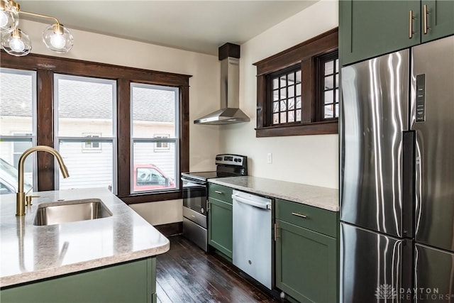 kitchen featuring wall chimney range hood, green cabinetry, and appliances with stainless steel finishes