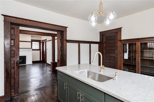 kitchen featuring sink, a chandelier, dark hardwood / wood-style flooring, pendant lighting, and light stone countertops