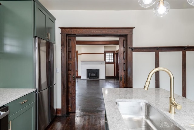 kitchen with stainless steel refrigerator, green cabinetry, dark hardwood / wood-style floors, and sink