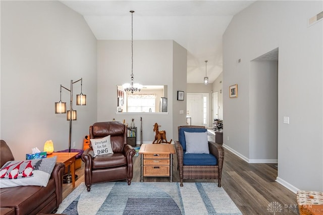 living area featuring an inviting chandelier, dark wood-type flooring, and high vaulted ceiling