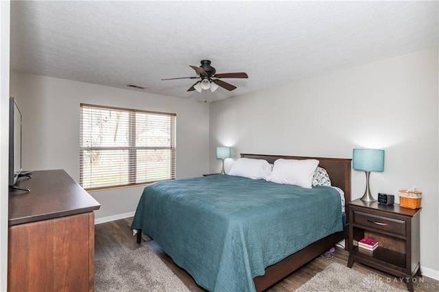 bedroom featuring dark wood-type flooring, a textured ceiling, and ceiling fan