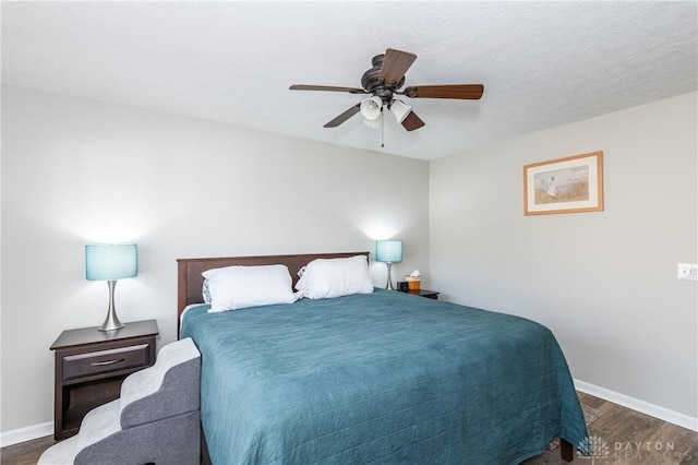 bedroom with a textured ceiling, dark wood-type flooring, and ceiling fan