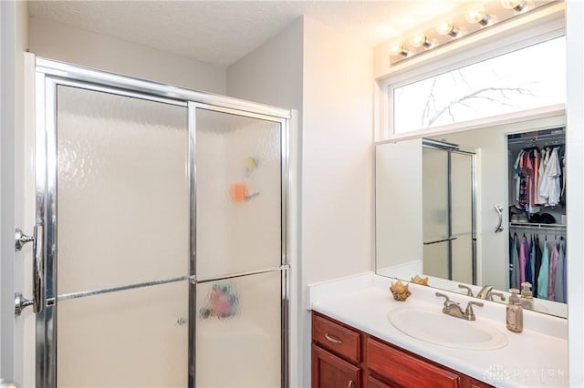 bathroom featuring vanity, a shower with door, and a textured ceiling