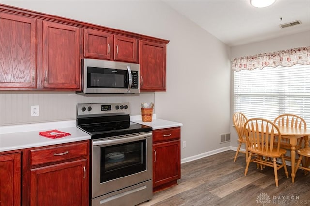 kitchen with hardwood / wood-style flooring, appliances with stainless steel finishes, and vaulted ceiling