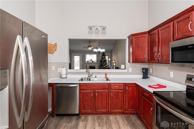 kitchen with pendant lighting, sink, stainless steel appliances, a chandelier, and light wood-type flooring