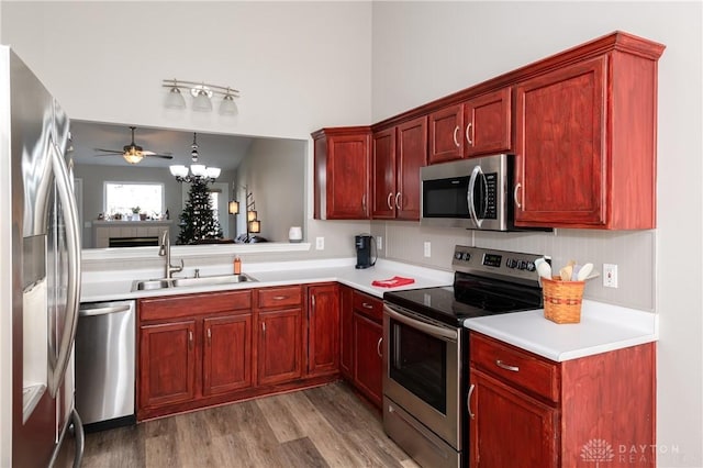 kitchen with appliances with stainless steel finishes, decorative light fixtures, sink, a notable chandelier, and light hardwood / wood-style floors