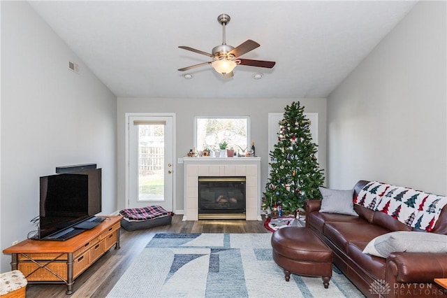 living room with dark hardwood / wood-style flooring, vaulted ceiling, a tile fireplace, and ceiling fan