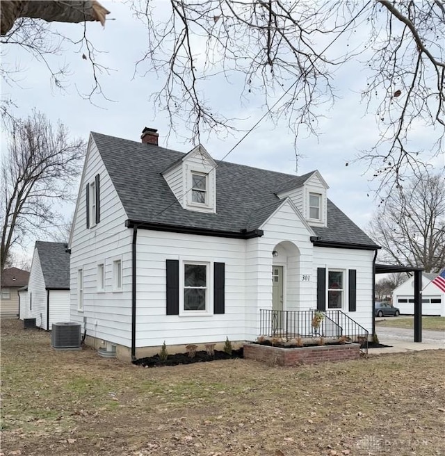 new england style home with central AC unit and a front lawn