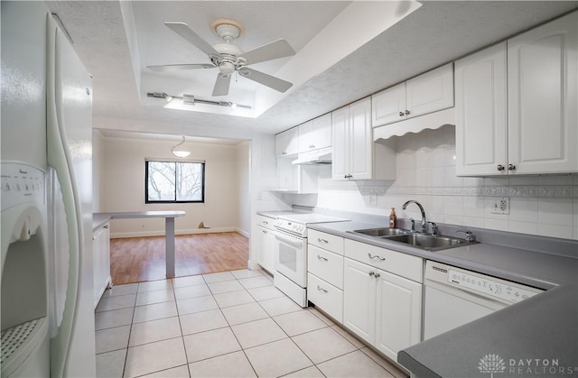 kitchen featuring white cabinetry, sink, decorative backsplash, a tray ceiling, and white appliances