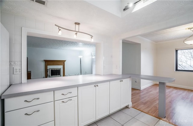 kitchen featuring white cabinetry, light hardwood / wood-style floors, a textured ceiling, and kitchen peninsula