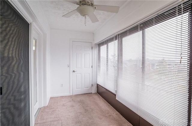 hallway with light carpet and a textured ceiling