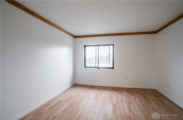 empty room featuring crown molding, light hardwood / wood-style floors, and a textured ceiling