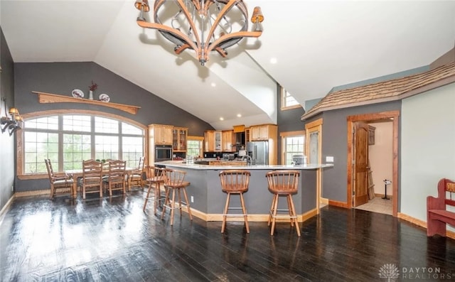 kitchen featuring appliances with stainless steel finishes, a breakfast bar, hardwood / wood-style floors, light brown cabinetry, and kitchen peninsula
