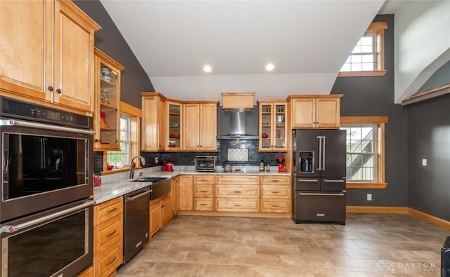 kitchen featuring double oven, dishwasher, decorative backsplash, high end fridge, and wall chimney range hood