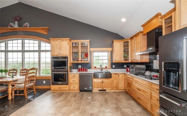 kitchen with sink, tasteful backsplash, vaulted ceiling, light brown cabinets, and black appliances