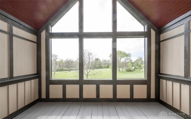 unfurnished sunroom featuring lofted ceiling, wood ceiling, and plenty of natural light