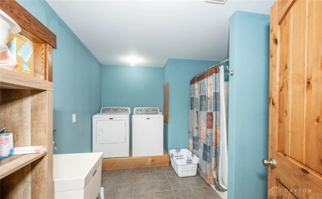 clothes washing area with washing machine and clothes dryer and dark tile patterned floors