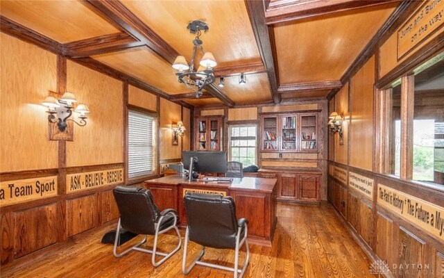 home office featuring light hardwood / wood-style flooring, beam ceiling, wooden walls, coffered ceiling, and a notable chandelier