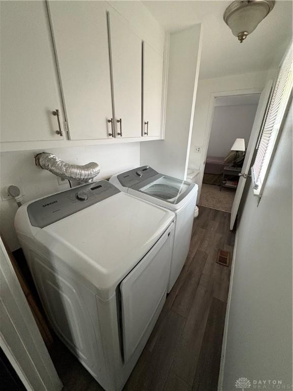 washroom with separate washer and dryer, dark hardwood / wood-style floors, and cabinets