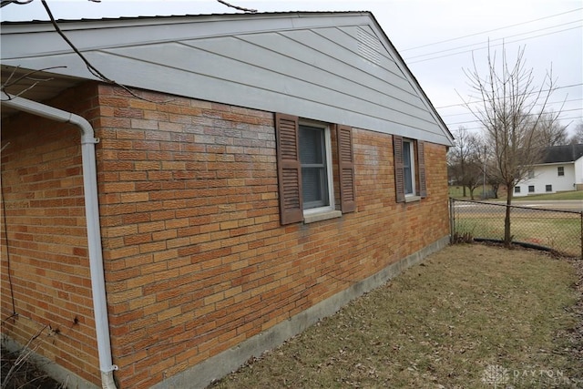 view of home's exterior with fence and brick siding