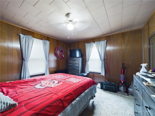 bedroom with carpet floors, ceiling fan, and wood walls