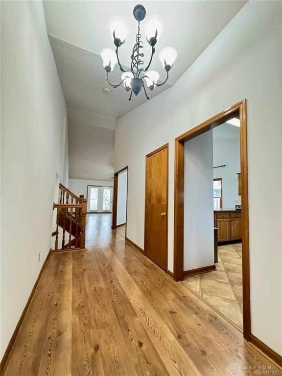 hallway with lofted ceiling, light hardwood / wood-style flooring, and a chandelier