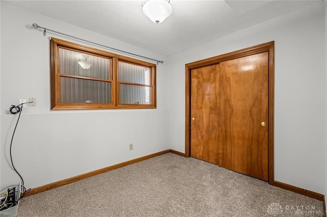 unfurnished bedroom with light colored carpet, a textured ceiling, and a closet