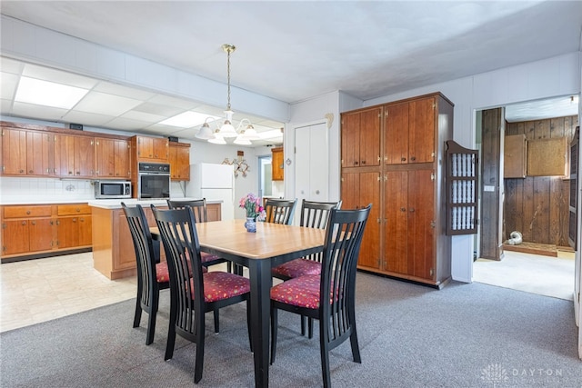 carpeted dining room featuring an inviting chandelier and wood walls