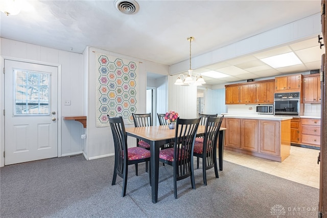 carpeted dining space featuring an inviting chandelier