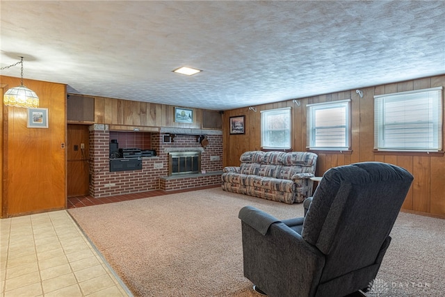 living room with a textured ceiling, a brick fireplace, wooden walls, and light colored carpet