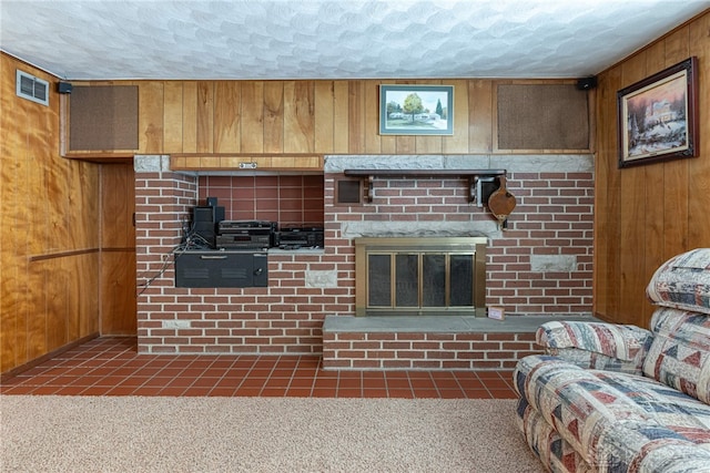 carpeted living room featuring a brick fireplace, wood walls, and a textured ceiling