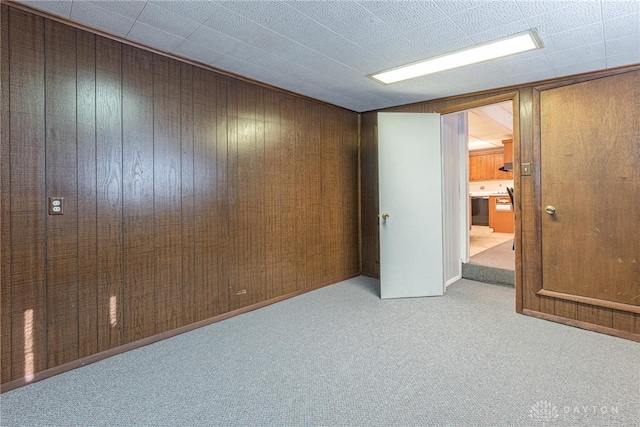 carpeted spare room with wood walls