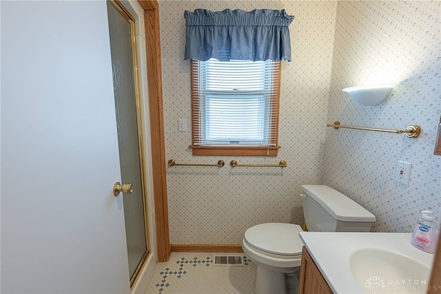 bathroom with tile patterned floors, toilet, vanity, and an enclosed shower