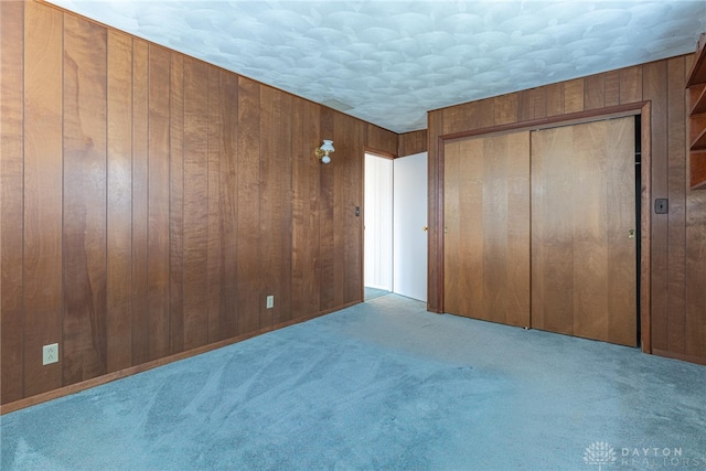 unfurnished bedroom featuring a closet, wood walls, and light colored carpet