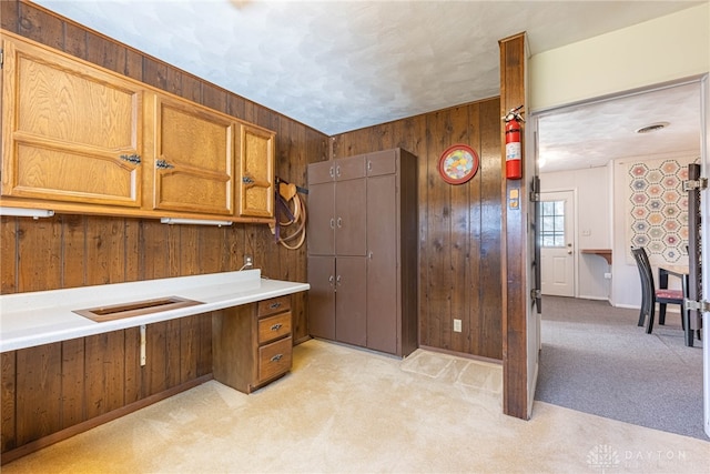 kitchen featuring wooden walls and light colored carpet