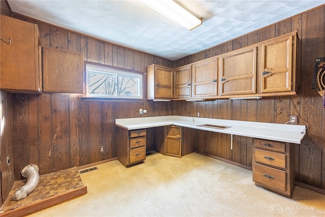 unfurnished office featuring built in desk, light colored carpet, and wood walls