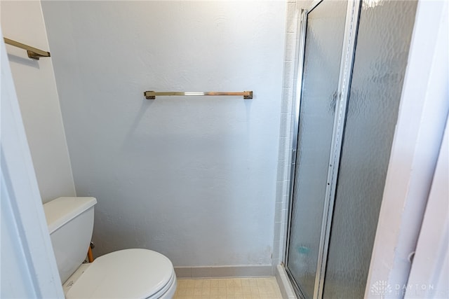 bathroom featuring a shower with door and toilet