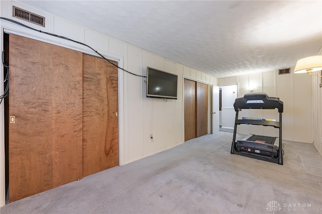 workout room with a textured ceiling and light colored carpet