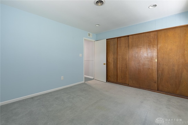 unfurnished bedroom with a closet and light colored carpet