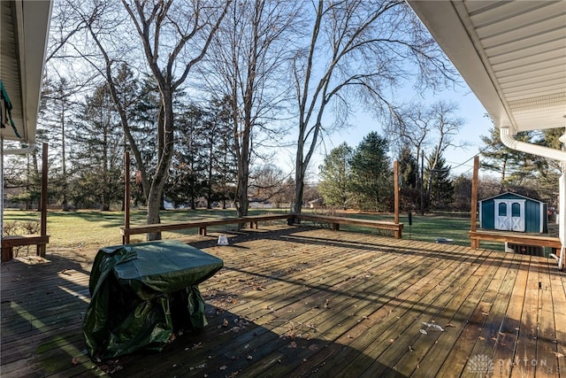 wooden deck featuring a storage unit and a grill