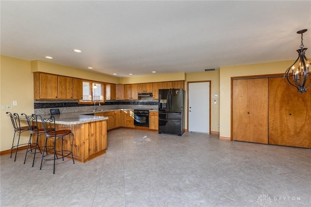 kitchen with a kitchen bar, black appliances, kitchen peninsula, pendant lighting, and backsplash