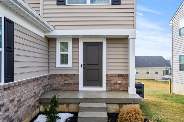 property entrance featuring a yard and central air condition unit