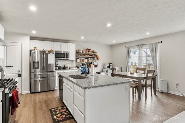 kitchen featuring white cabinetry, sink, a kitchen island with sink, light stone counters, and stainless steel appliances