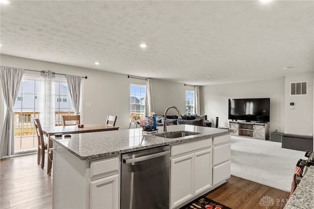 kitchen with dishwasher, an island with sink, sink, white cabinets, and light stone counters