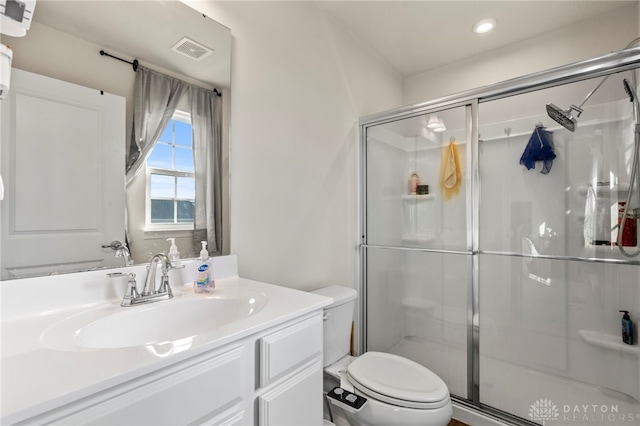 bathroom with vanity, toilet, and a shower with shower door