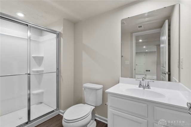 bathroom featuring vanity, toilet, a shower with door, and hardwood / wood-style floors