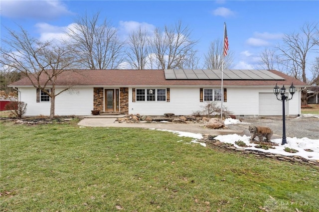 ranch-style home with a garage, a front lawn, and solar panels