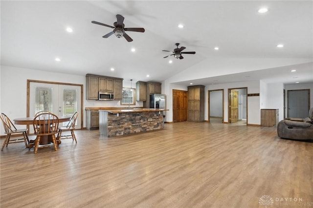 living room with ceiling fan, lofted ceiling, light wood-type flooring, and french doors