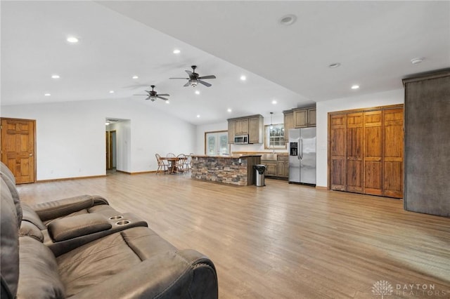 living room featuring vaulted ceiling, light hardwood / wood-style floors, and ceiling fan